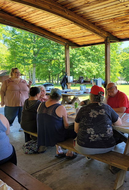 A speaker with people seated at a picnic table listening
